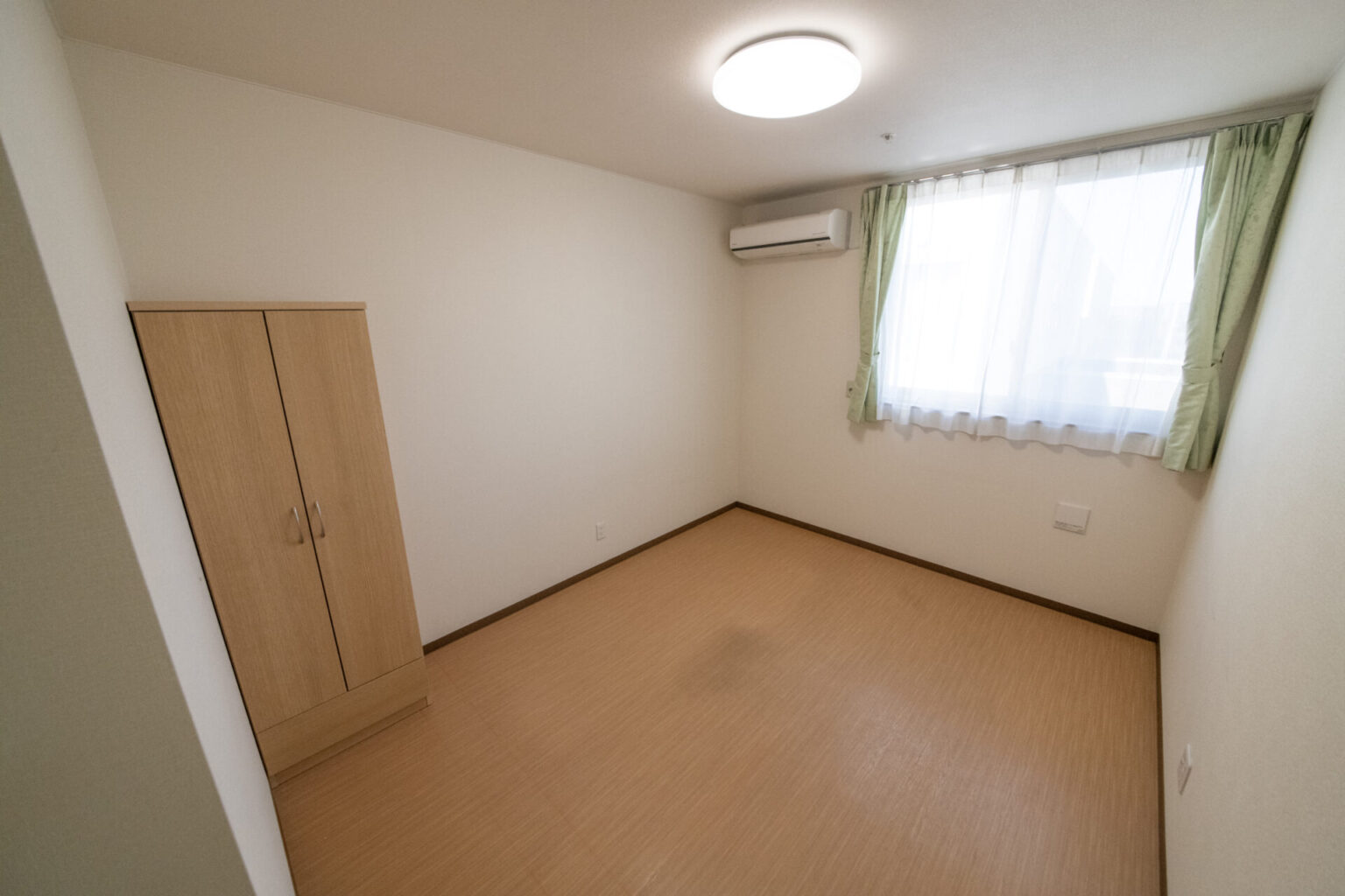 木製クローゼット付きの明るい居室。南向き窓から採光が入る。